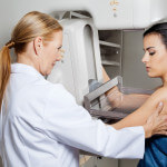 Doctor Assisting Patient Undergoing Mammogram