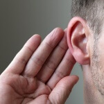 אדם חרש שמסמן עם היד שלו על האוזן